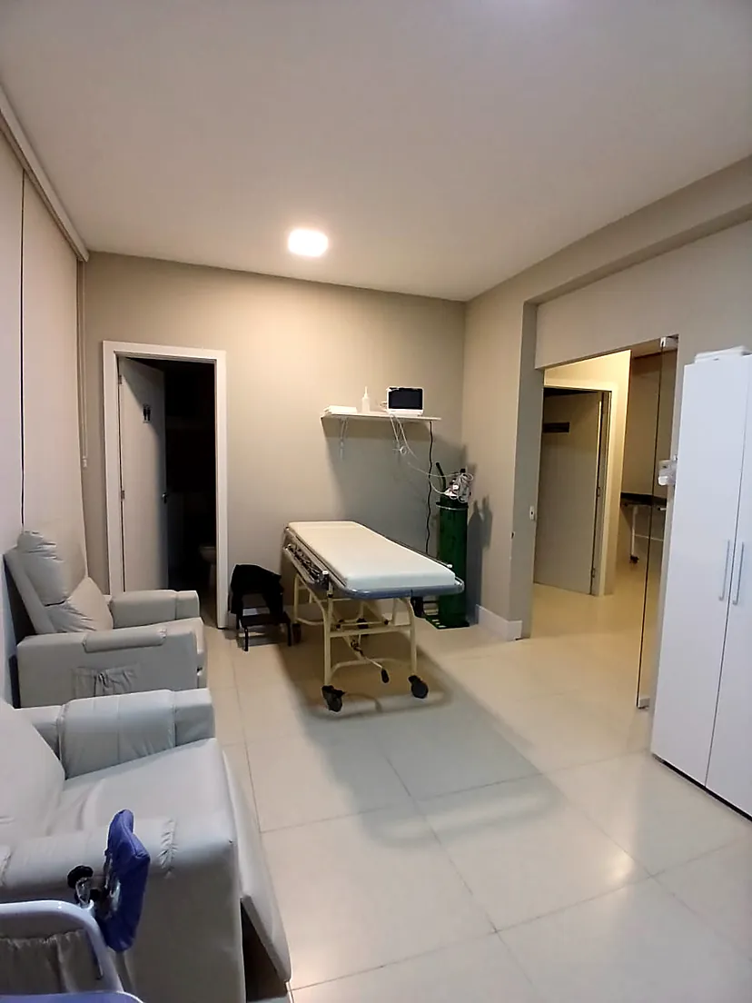 Corredor interno da clínica com maca e poltronas de atendimento
